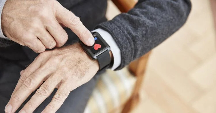 Person pressing a medical alert smartwatch with heart rate indicator