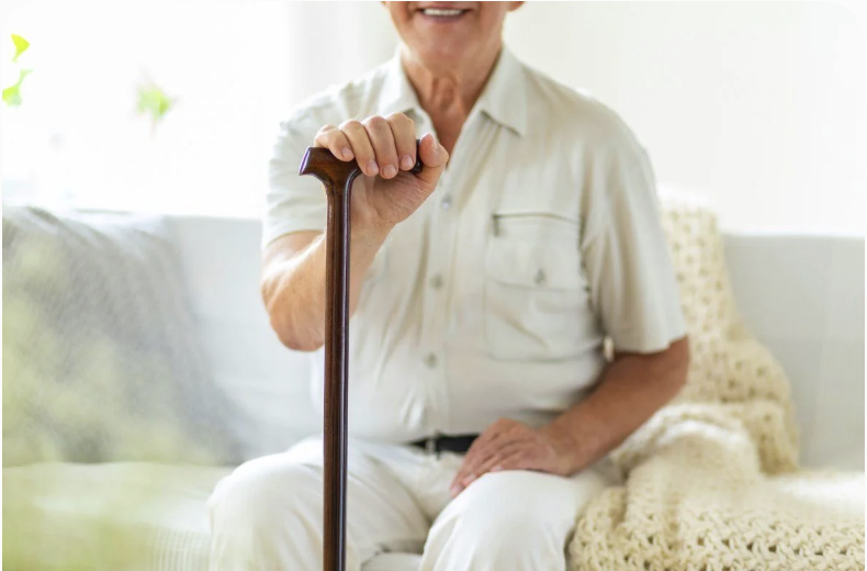Senior man seated indoors holding a walking cane