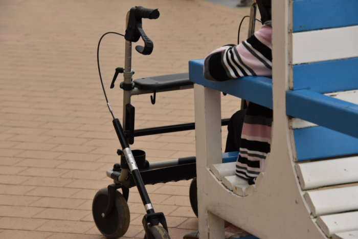 Senior person resting near steps with a rollator parked beside them